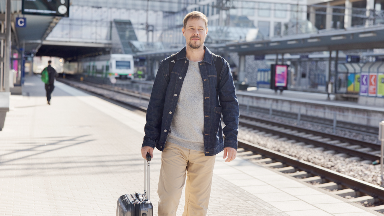  En man med en resväska på tågstationen.