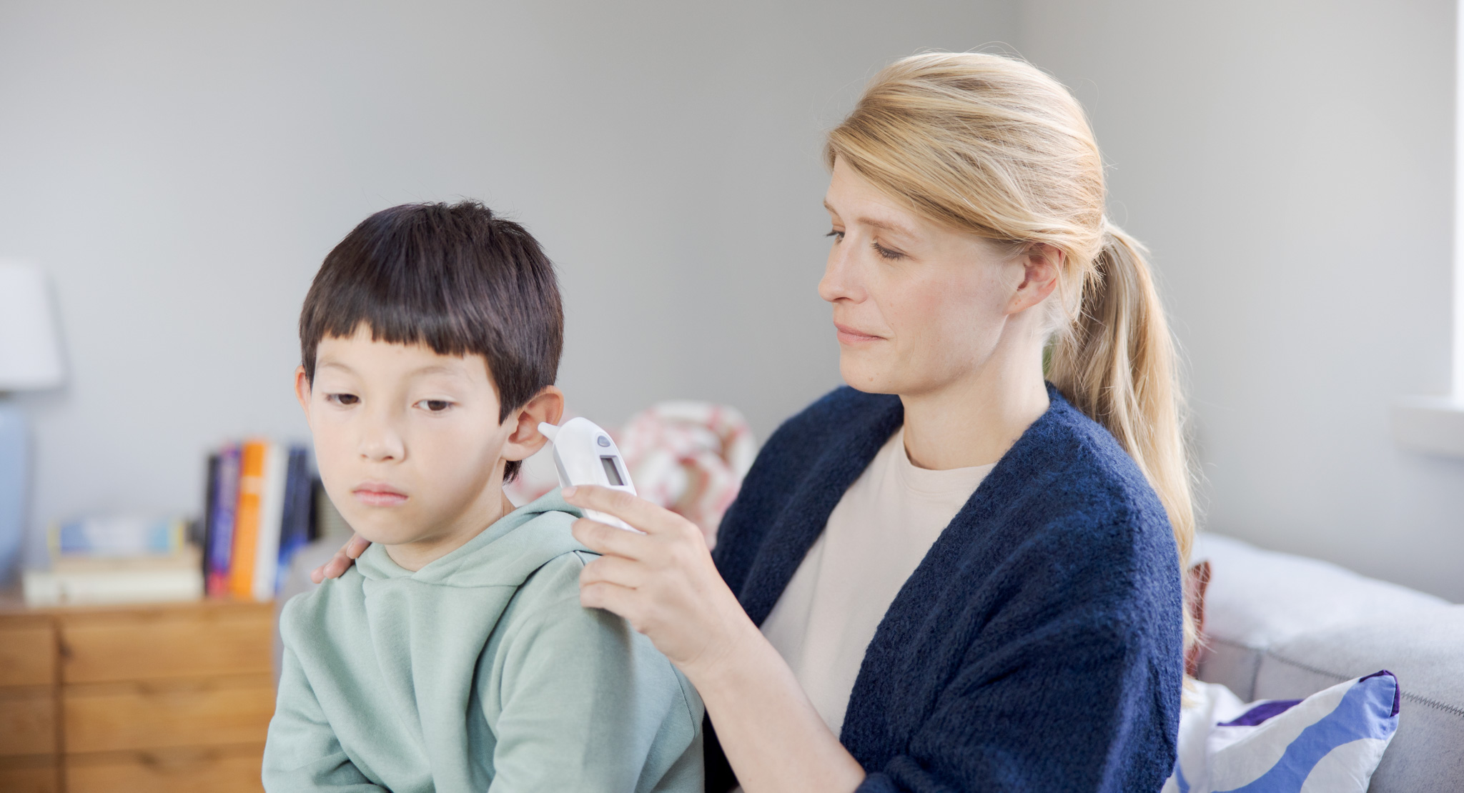 A woman is taking a child's temperature.